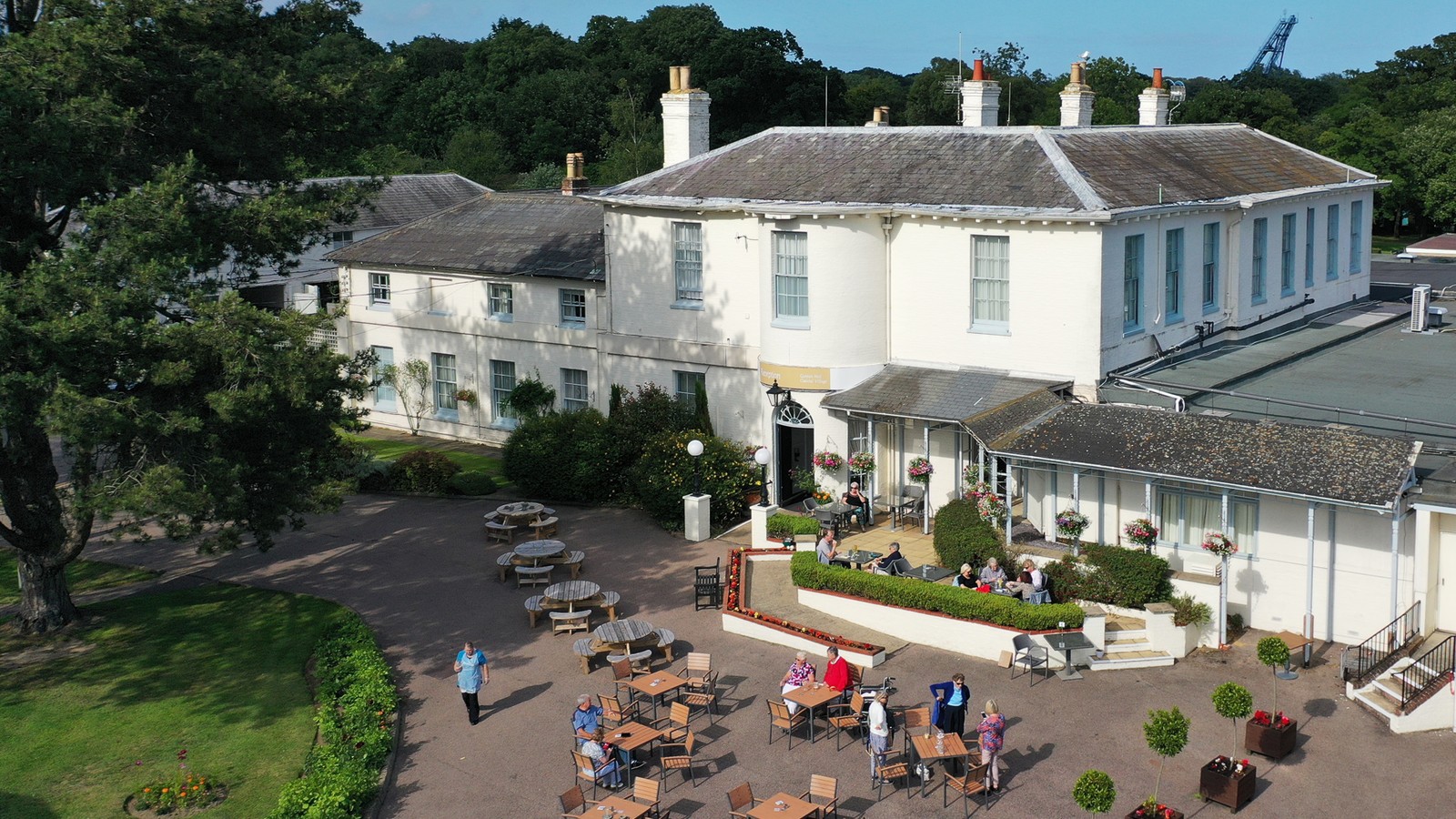 Aerial view of Gunton Hall main building set among lush greenery.