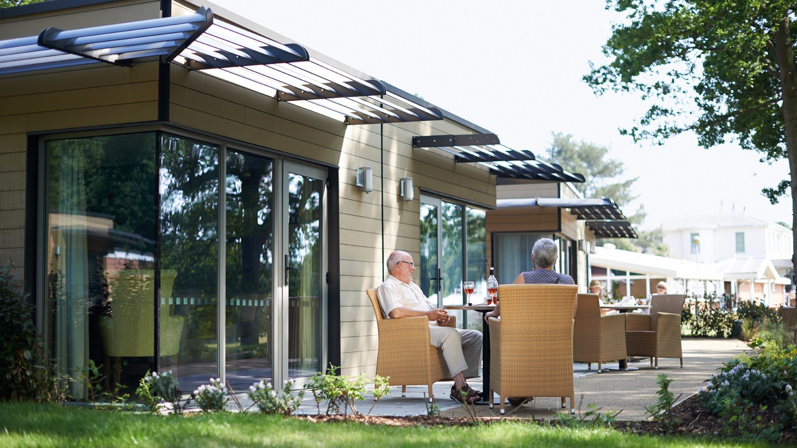 Outside view of the garden lodges with comfortable seating surrounded by nature.
