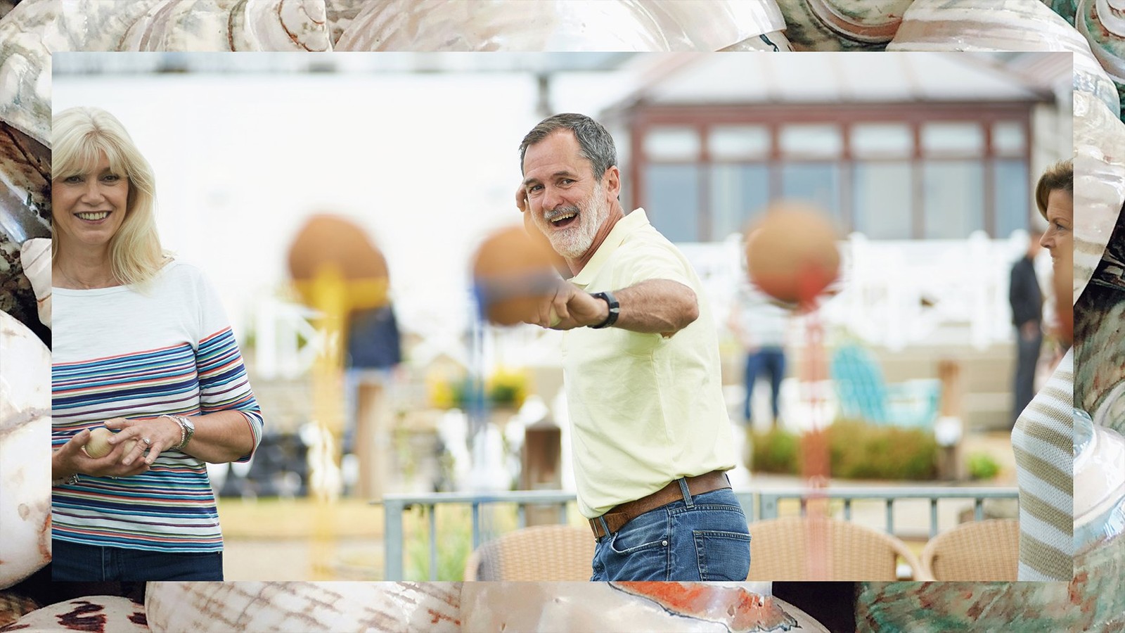 A gentleman preparing to throw a ball at the coconut shy, one of the many games found on the grounds at Corton, a Warner Village. The border depicts sea shells that have been used to decorate the nautically-themed hotel rooms.