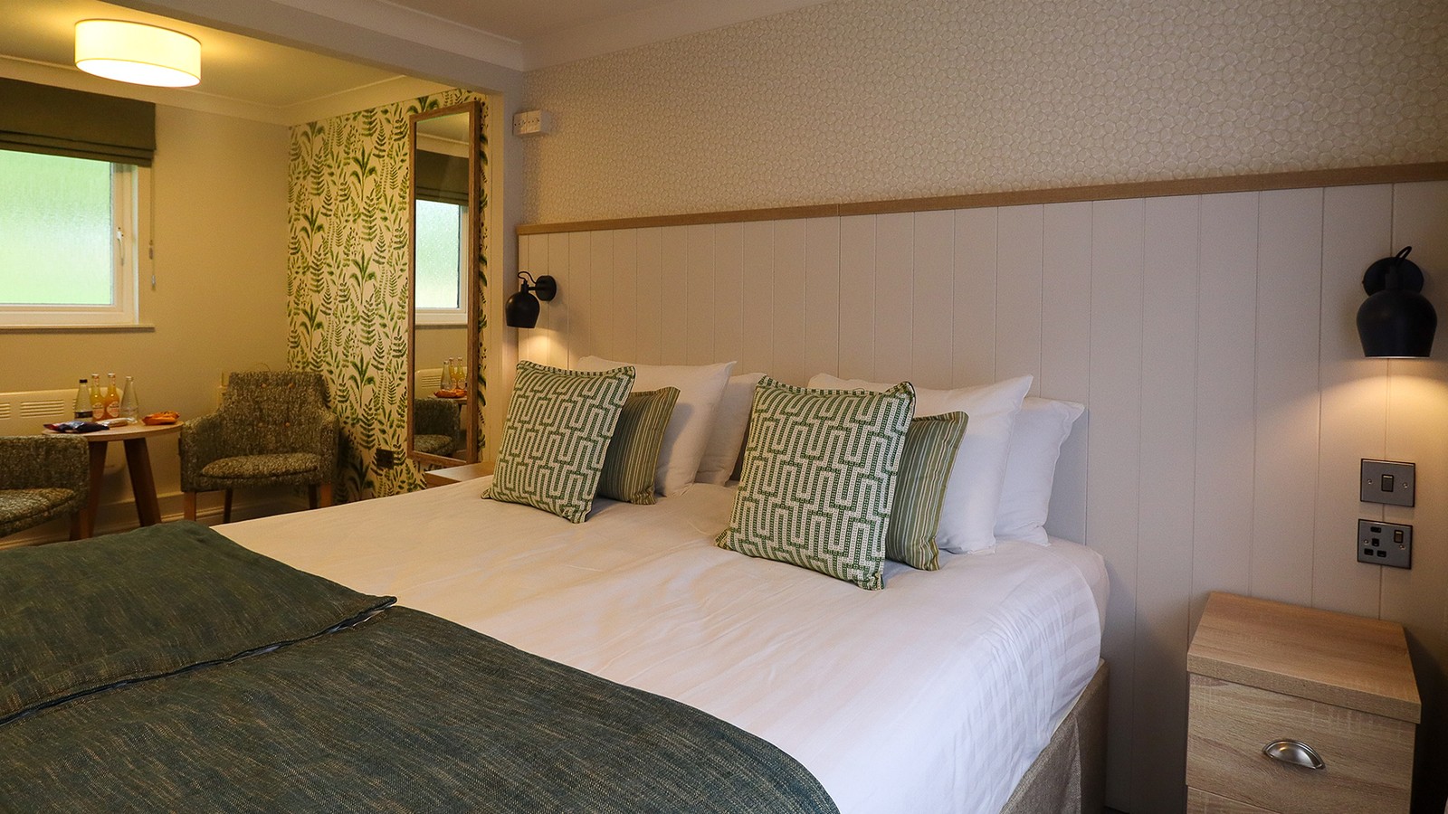 A comfortable Premier chalet room at Gunton Hall featuring a comfortable bed and seating area.