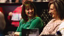 Two women at a table, smiling and enjoying each other's company during a BBC History Magazine weekend event.