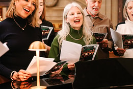 A group of guests carol singing and smiling