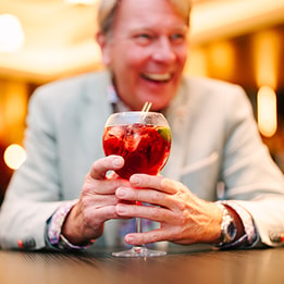 A guest laughing as he holds his festive cocktail