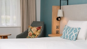 Close-up of a bedroom seating area beside a king-size bed and window.