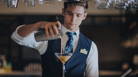 A bartender pours a cocktail from a shaker