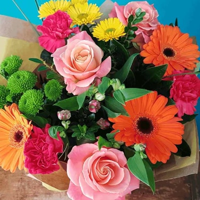 A vibrant bouquet of assorted flowers beautifully arranged in a rustic paper bag, adding charm to any setting.