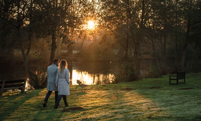 Couple holding hands walking by the Lake at Gunton Hall