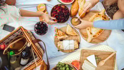 Aerial view of a picnic blanket with delicious summer fruits, cheeses, breads and more