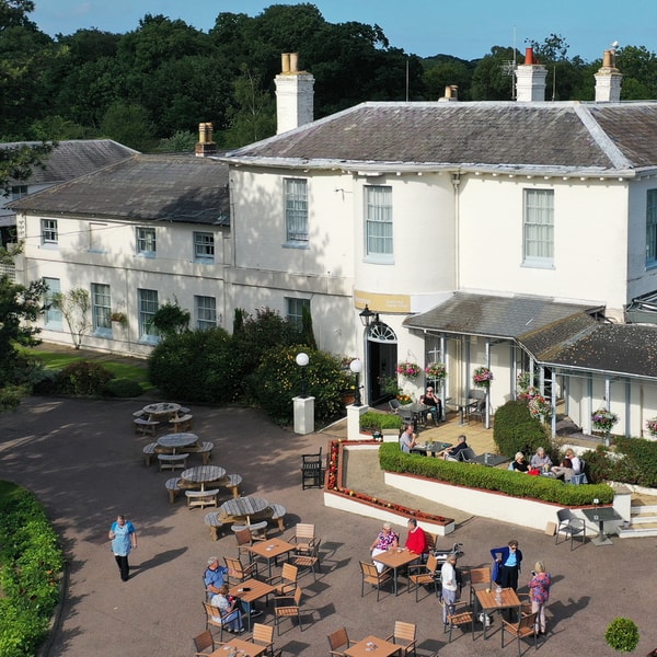 Aerial view of Gunton Hall main building set among lush greenery.