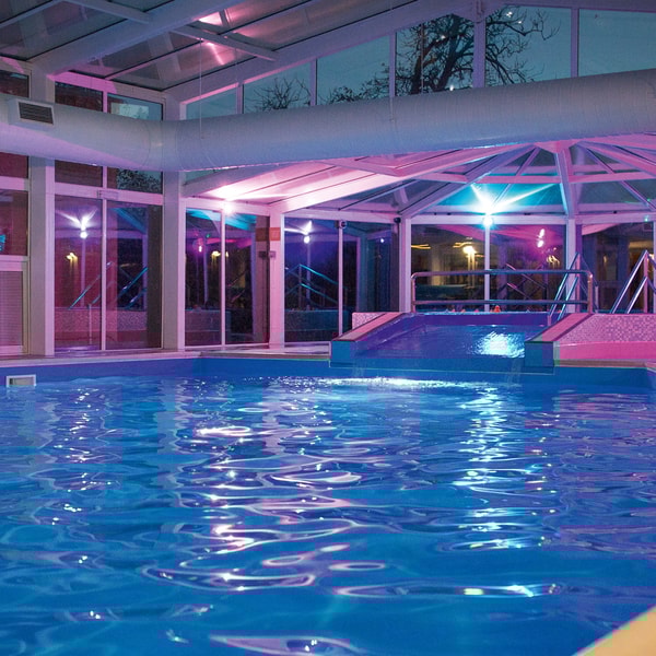 Indoor large pool in the evening with bright lighting.