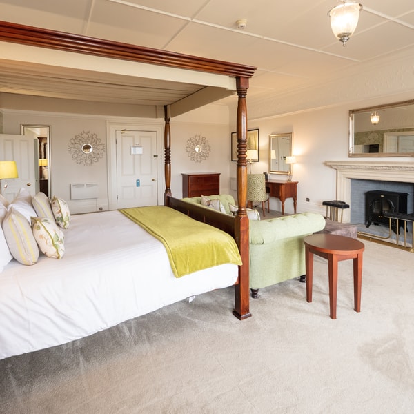 A historic room in the main building featuring a large four poster bed and ample additional seating.