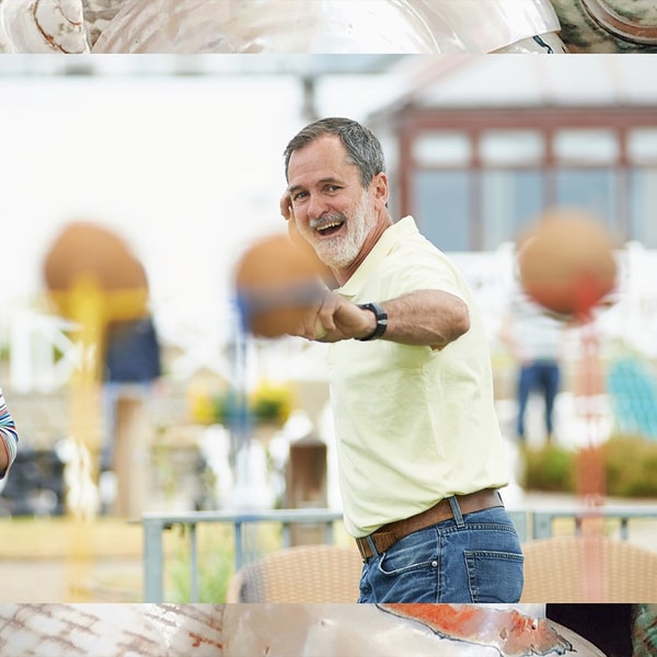 A gentleman preparing to throw a ball at the coconut shy, one of the many games found on the grounds at Corton, a Warner Village. The border depicts sea shells that have been used to decorate the nautically-themed hotel rooms.