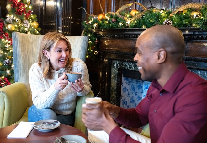 Two guests smiling at each other with hot drinks in hand