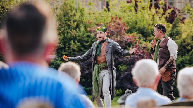 An actor on stage performing at the Outdoor Theatre to an audience of Warner Hotel guests