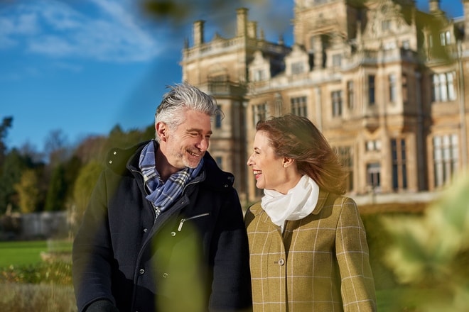 A couple smiling at each other in winter coats as they enjoy a stroll during their Valentine's weekend getaway