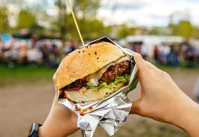 A delicious looking burger with a background of a food festival