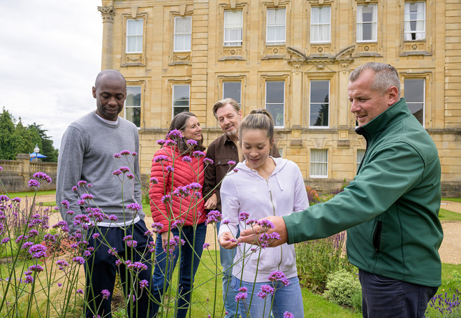 Guests having a tour of the gardens and grounds at Heythrop Park, lead by one of the grounds keepers