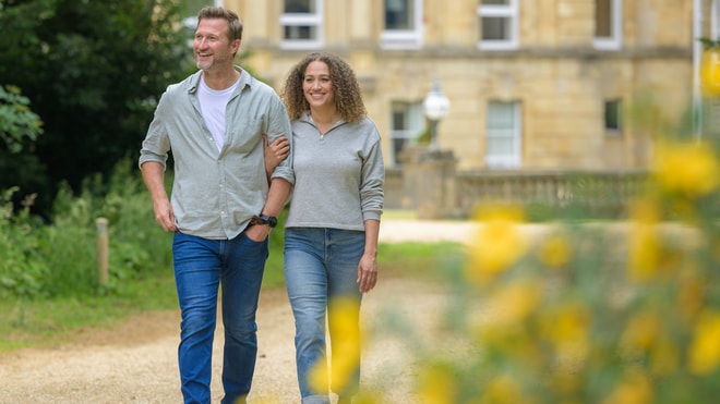 A couple walks side by side in front of the Heythrop building