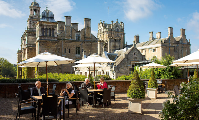 Some guests are enjoying drinks and snacks on the terrace on a warm day at Thoresby Hall Hotel