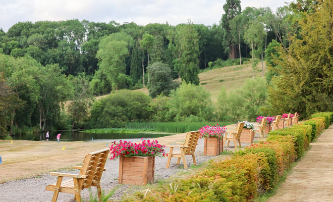 The grounds of Holme Lacy House featuring several benches lined up with flower pots in between