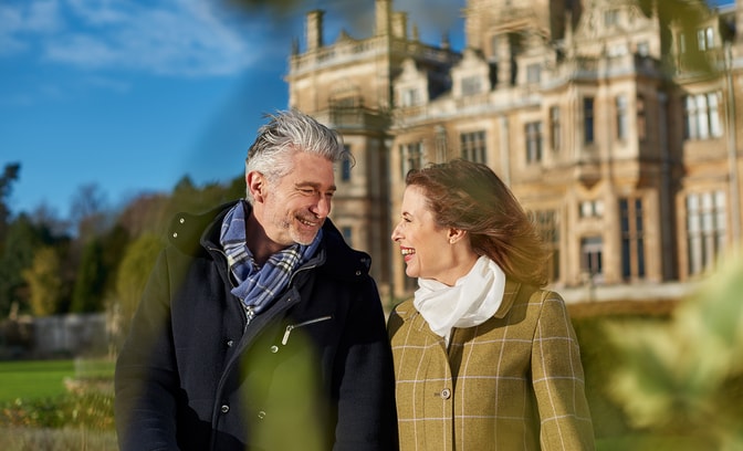 A couple smiling at each other in winter coats as they enjoy a stroll during their Valentine's weekend getaway