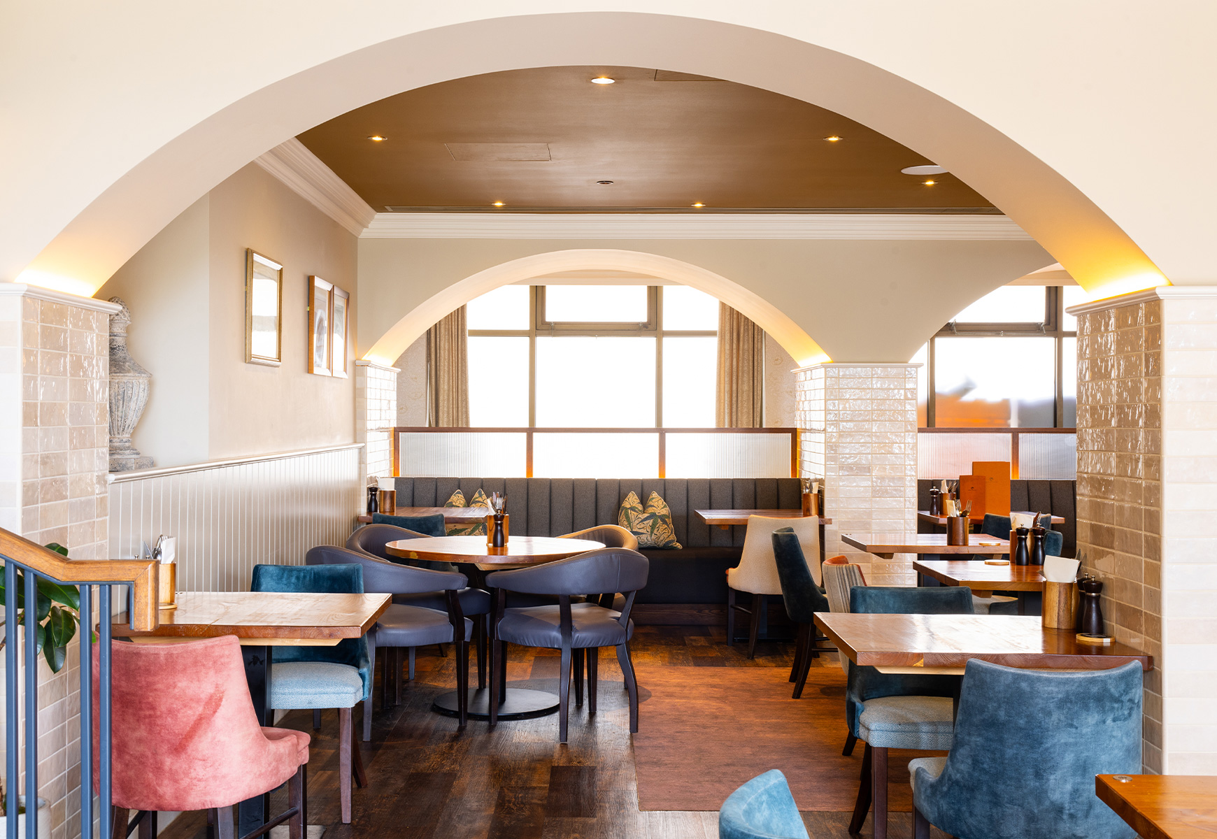 restaurant with upholster velvet chairs and a curved ceiling arch