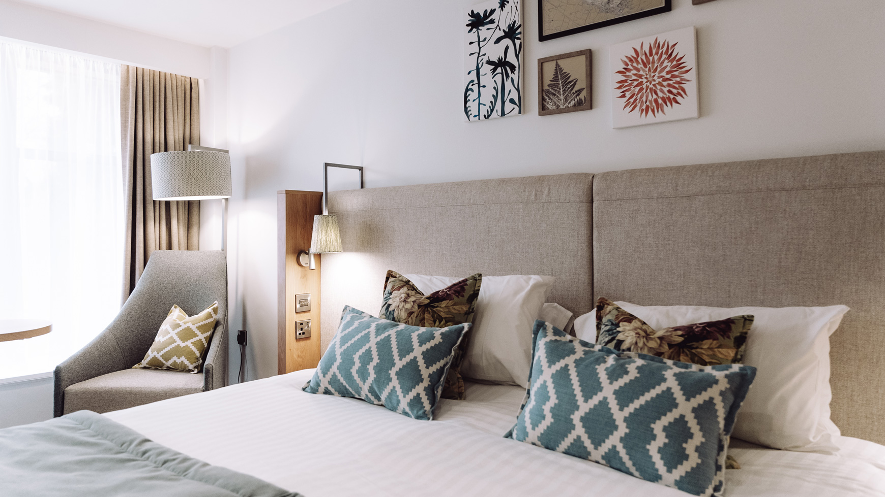 Close up of a double bed with patterned throw pillows