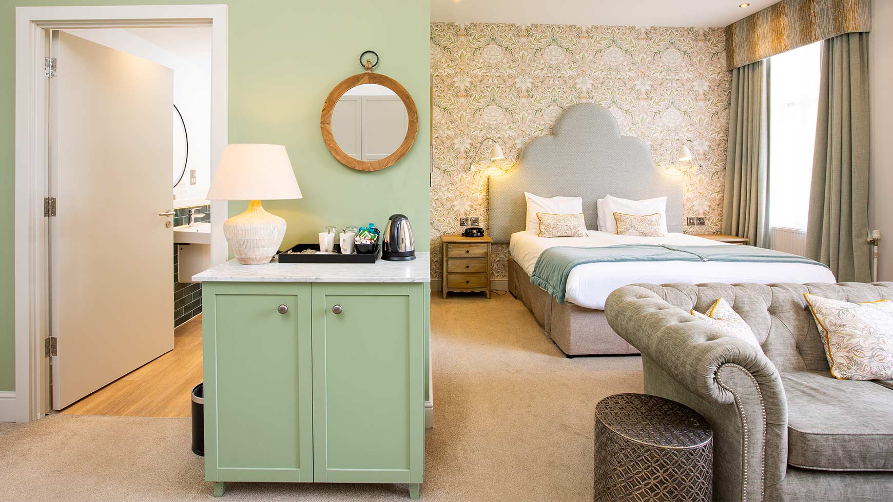 Large bedroom with a double bed, sofa, cabinet with tea tray and a door leading to a bathroom