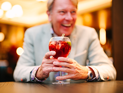 A guest laughing as he holds his festive cocktail