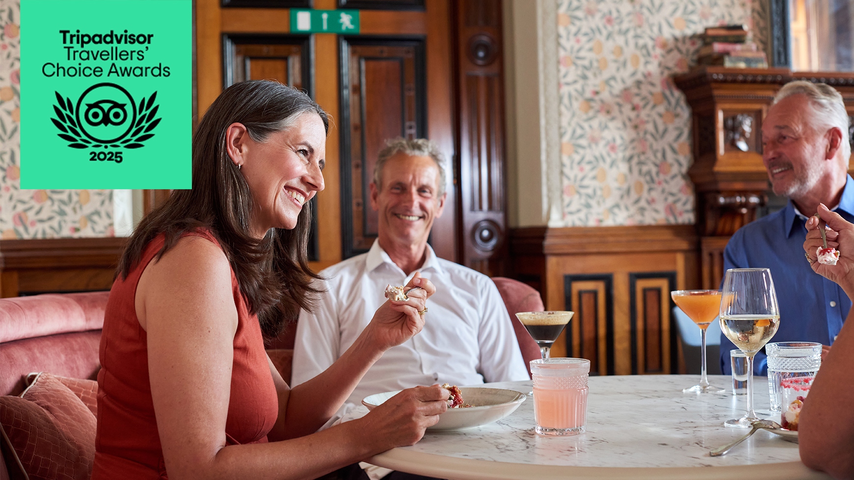 People enjoying a meal together and smiling with the Travellers' Choice award winner logo overlaid
